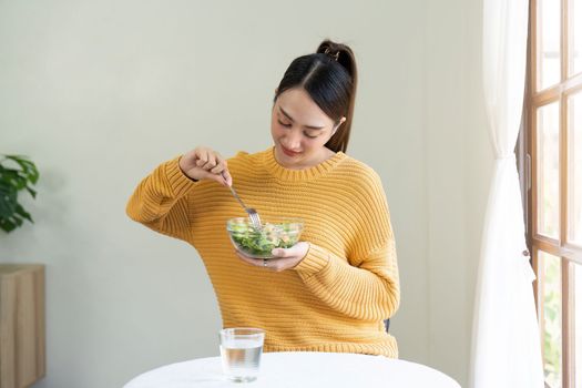 Delighted woman eating food for health at home