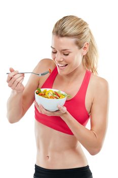 Nothing looks as good as healthy feels. Studio shot of an athletic young woman eating a bowl of salad.