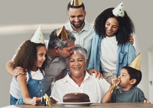 Family, birthday celebration and senior woman at a table with a cake, love and care in a house. Children, parents and grandparents together for a party to celebrate excited grandma with dessert