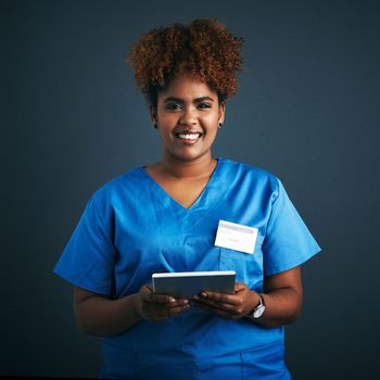 Lets consult online. Studio shot of a young doctor using a digital tablet against a gray background.