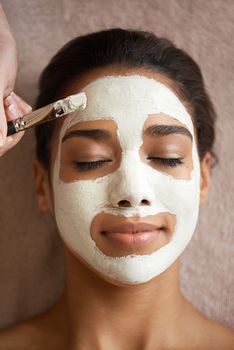 Treating herself to a luxurious facial mask. a young woman receiving a facial treatment at a spa.