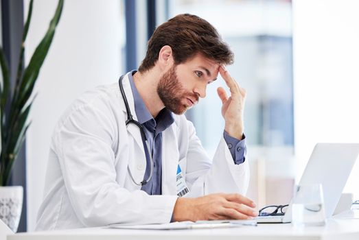 Headache, stress and anxiety of doctor on laptop reading hospital data, results and news fail, mistake or error. Tired, burnout or depression of medical professional with mental health research on pc