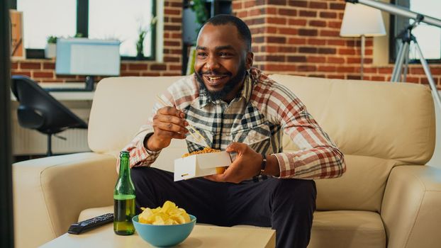 African american man enjoying asian food in delivery box