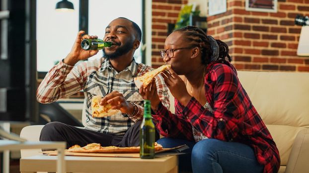 Young couple laughing and eating pizza