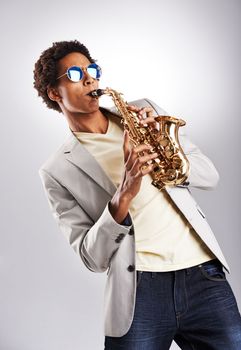 Do it with passion or not at all. Studio shot of a fashionable young man playing the saxophone.