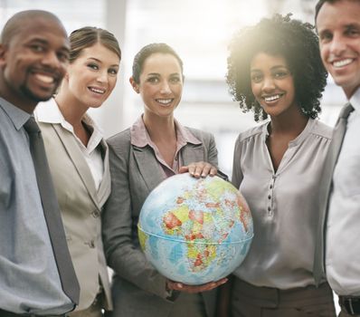 Ready to take on the world. Cropped portrait of a businesswoman holding a globe while standing with her colleagues.