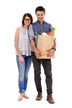 Theyre organically modern. Studio portrait of a couple with groceries isolated on white.