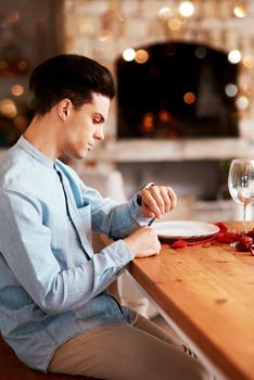Romance, waiting and man checking the time while sitting in the restaurant for a valentines day date. Fine dining, late and guy by the table for dinner reservation for anniversary or romantic event.