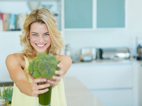 The health benefits are endless. Portrait of a happy young woman holding a broccoli shake.
