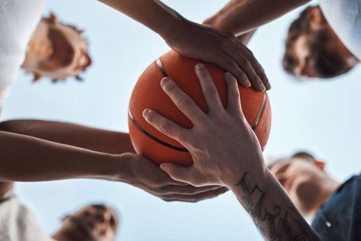 Sport is a great way to teach teamwork. Closeup shot of a group of sporty young men huddled around a basketball on a sports court.