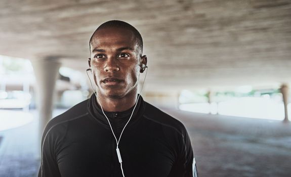 Focused on his training. a sporty young man listening to music while exercising outdoors.