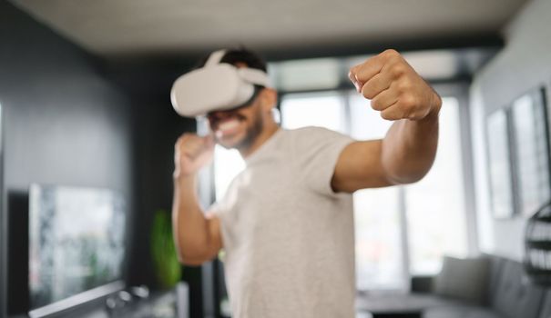 VR, metaverse and man boxing on a game, training for a fight and match. Futuristic, digital sports and gamer punching while playing in an augmented reality with technology glasses in a house