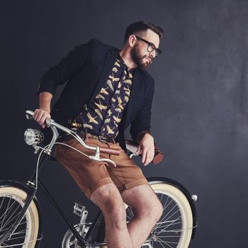 Just a trendy kind of guy. a trendy young man posing in studio with his bicycle.