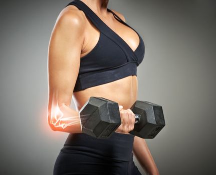 Making this look easy. Studio shot of an unrecognizable young woman holding a dumbbell while CGI shows an injury in her elbow.