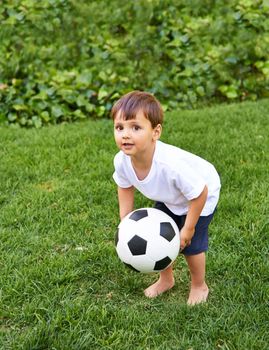Practice is everything. an adorable little boy playing with a soccer ball outside.