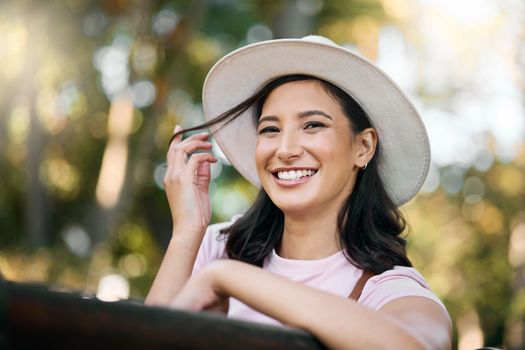Woman, park and portrait of a female traveler on a garden bench with a smile from travel. Freedom, happiness and hair twirl of a Asian person on holiday feeling happy on vacation enjoying nature