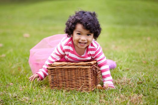 I bet all the picnic goodies are in this basket. an adorable little girl playing with a picnic basket on the lawn.