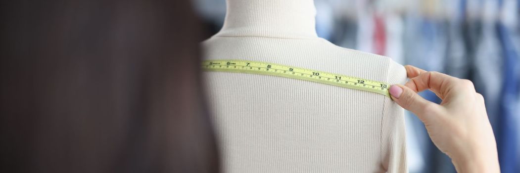 Fashion designer stylist takes measurements with centimeter from clothes on mannequin. Atelier services concept