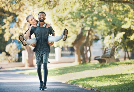 Interracial couple, piggy back and outdoor with smile for fitness, health and exercise in park. Runner, black man and woman on back in workout, running or wellness in urban sunshine by trees together