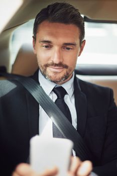 Using a navigation app means hes more punctual and professional. a businessman using his phone while traveling in a car.