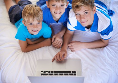 Kids of today are so tech savvy. Three brothers browsing the internet together on a laptop.