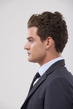His business mind will ensure success. an attractive young businessman standing against a gray background.