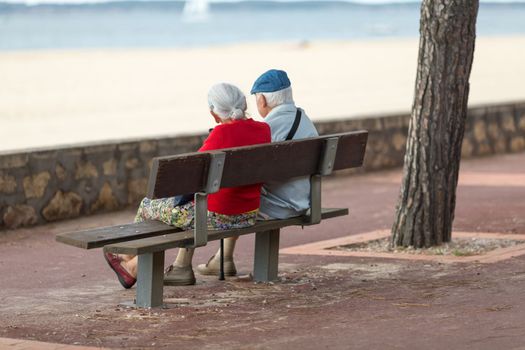 senior couple sitting on a bench looking at the sea