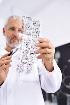 Having a look at your DNA profile. a male scientist analyzing the results of a DNA test.