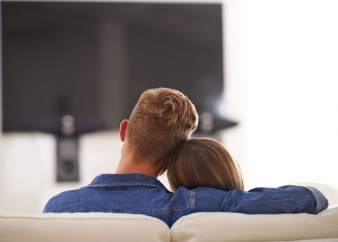 Lets cuddle on the couch all day. Young couple cuddling together in front of the TV.