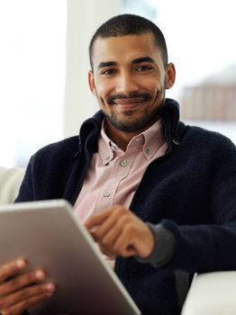Staying connected has never been easier. Portrait of a smiling young man working at home on a digital tablet.