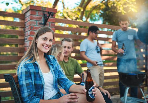 Todays chill session will be a grill session. a happy young woman enjoying a beer at a barbecue with her friends.