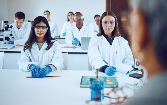 University, education and science students with professor in classroom. College books, learning and group of people, men and women in lab coats with teacher, lecturer or educator studying biology.