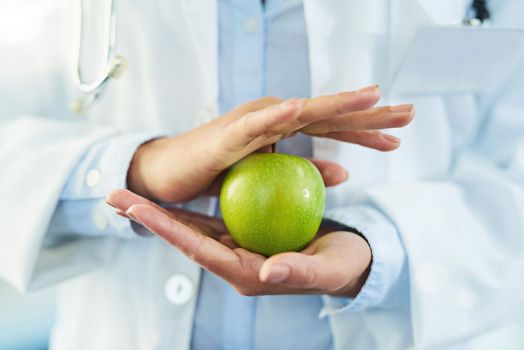 Take health into your own hands. Closeup shot of an unidentifiable doctor holding an apple.