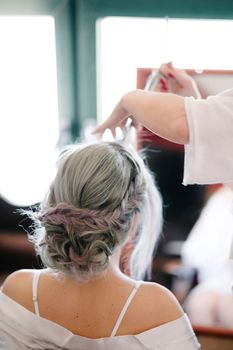 Hairdresser makes the bride an elaborate hairstyle. Close up