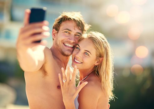 Check out my rock. a young woman showing off her wedding ring while taking a selfie with her husband.