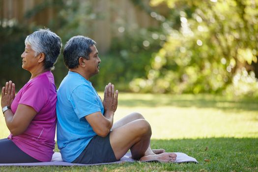 Keeping balanced and healthy. a mature couple doing yoga together in their backyard.