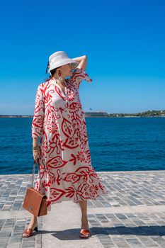 woman in a hat and dress enjoys the blue sea and summer. Welcome summer.