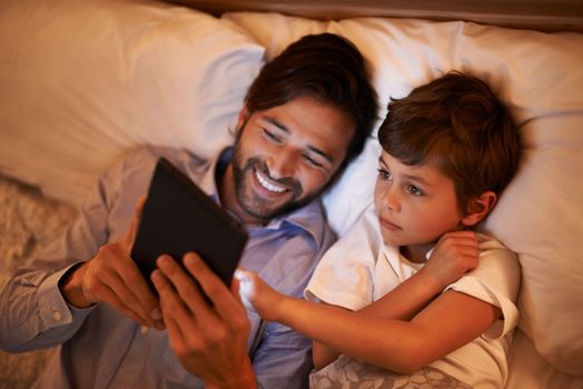 Modern bedtime story. A father reading a bedtime story to his son from an e-reader.