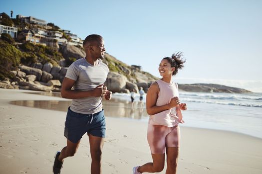 Couple, fitness and running with smile at the beach, exercise and cardio, happiness and active lifestyle. Young, happy people, runner and health, body training and motivation workout outdoor at ocean