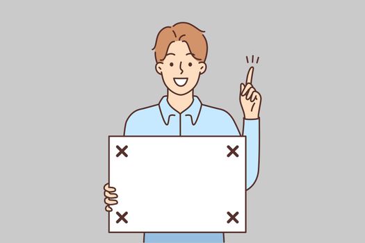 Smiling man with board in hands point up