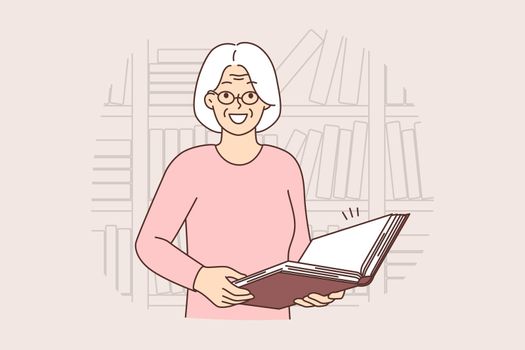 Smiling old woman with book in library