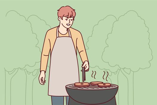 Man in apron cook meat outdoors