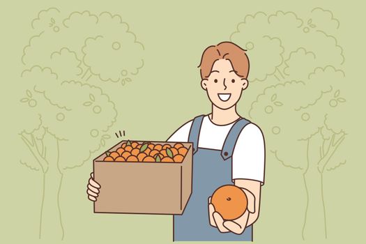 Smiling male farmer with box of fruits
