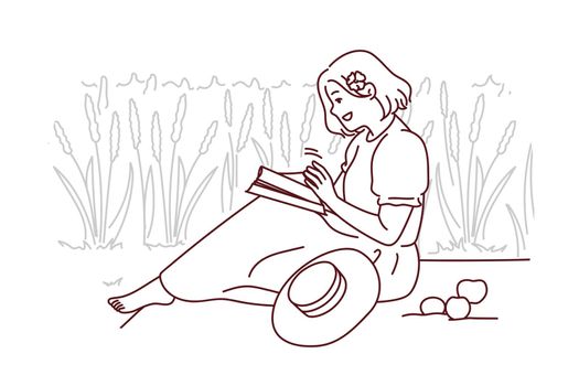 Woman sitting in field reading book