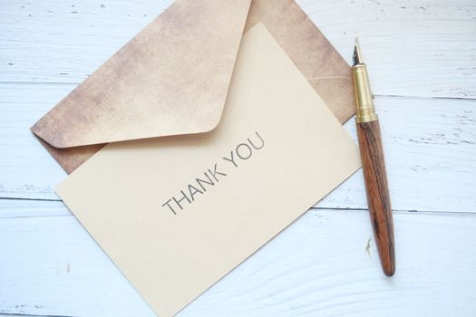thank you message and envelope on wooden table