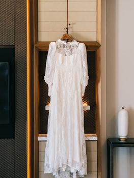 White wedding dress hangs on a closet door in a hotel room. High quality photo