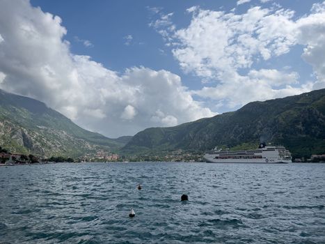 Huge passenger liner floats on the sea against the backdrop of mountains