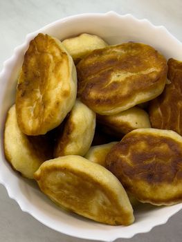 Fried pancakes lie in a deep bowl on the table