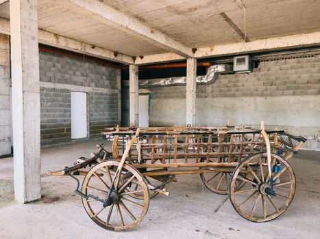 Wooden cart on wheels stands under a concrete canopy in a parking lot