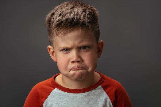 Preschool boy expresses sad emotions. Conflict concept. Close up portrait